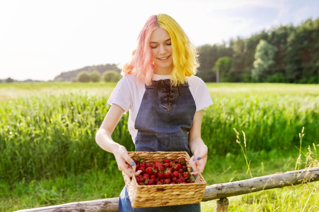 Young teenage girl with basket of fresh plucked strawberries